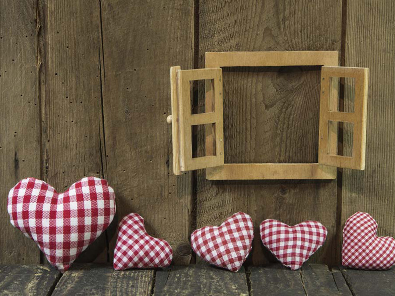 Cushioned hearts sat against a wooden wall with wooden window frame
