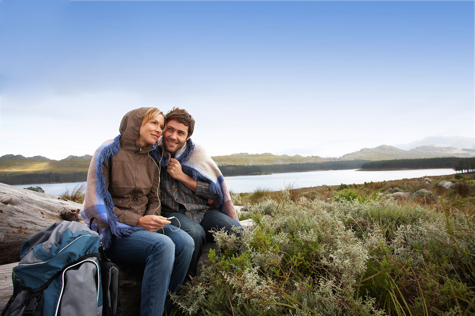 Couple sitting together looking the view of the countryside and lake