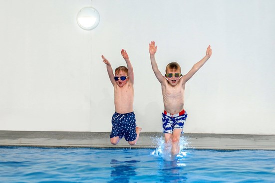 Children jumping into indoor swimming pool