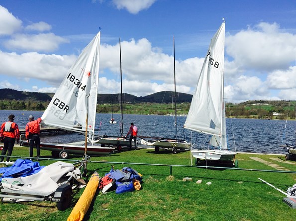 Men and small sailing boats on the grass in front of Lake Windermere