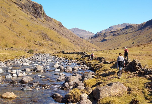 The flank of Scafell and 3000 foot Bowfell looking down on hikers beside the River Esk in upper Eskdale