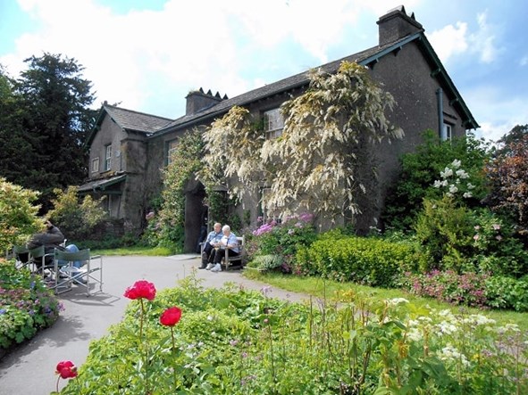 Couple sat on a bench in front of Beatrix Potter's former home, Hill Top
