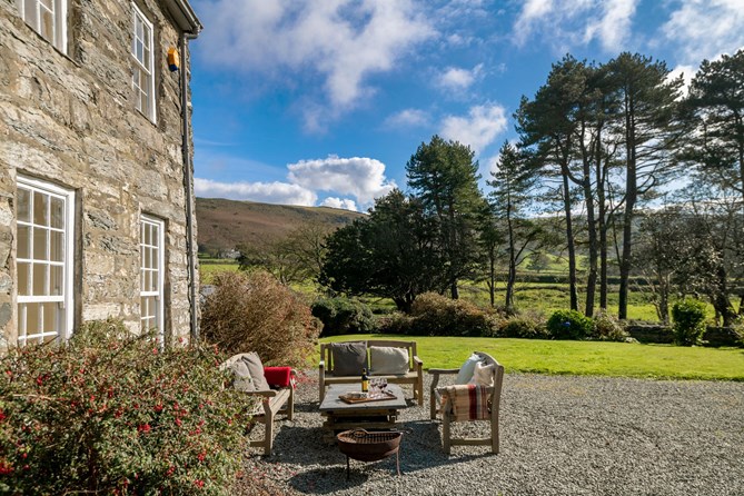 Wooden table and chairs outside a luxury holiday cottage with a view of trees and fields