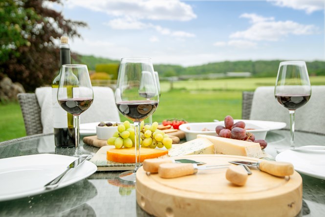 Cheese, grapes and wine on an outdoor dining table looking out to views