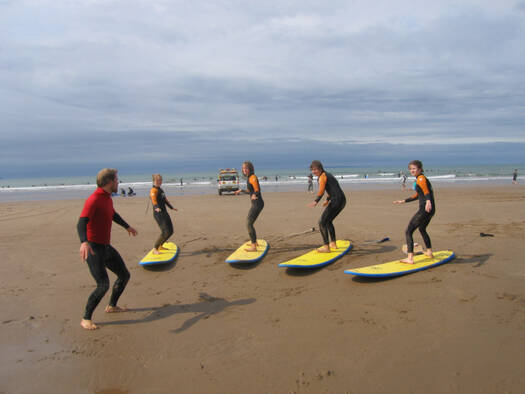 Group of teenagers being taught how to surf