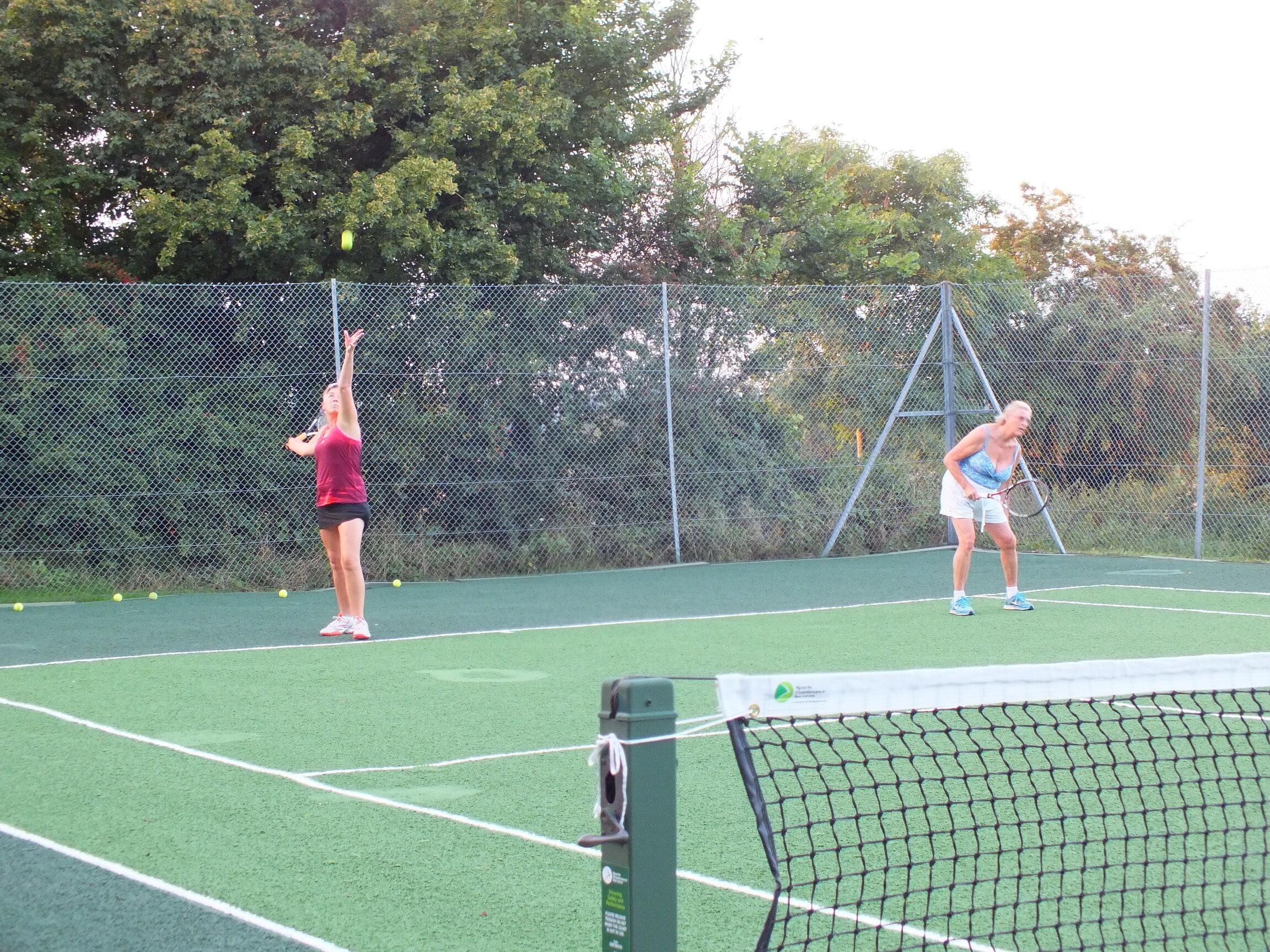 Two women playing tennis outdoors