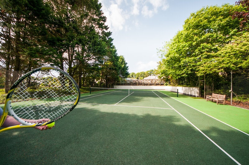 Person playing tennis on a court at a luxury holiday cottage