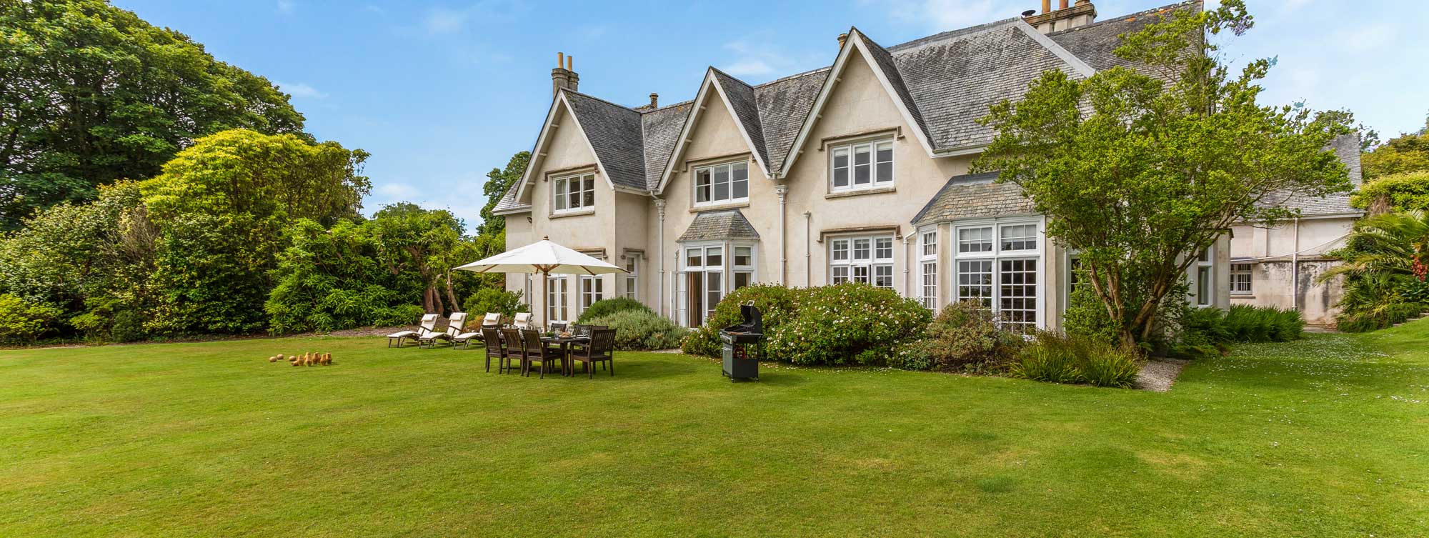 Exterior of a grand holiday cottage with outdoor furniture and lawn